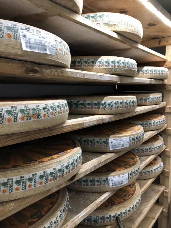 Meules de comté alignées sur des planches d’épicéa dans une cave d’affinage