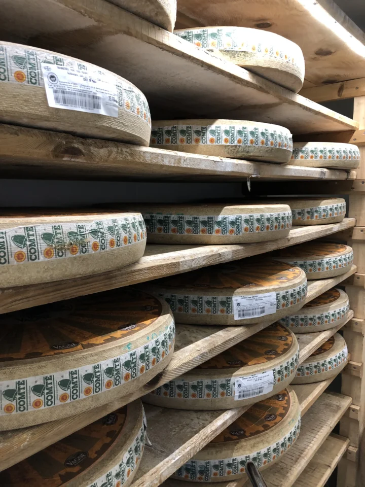 Meules de comté alignées sur des planches d’épicéa dans une cave d’affinage