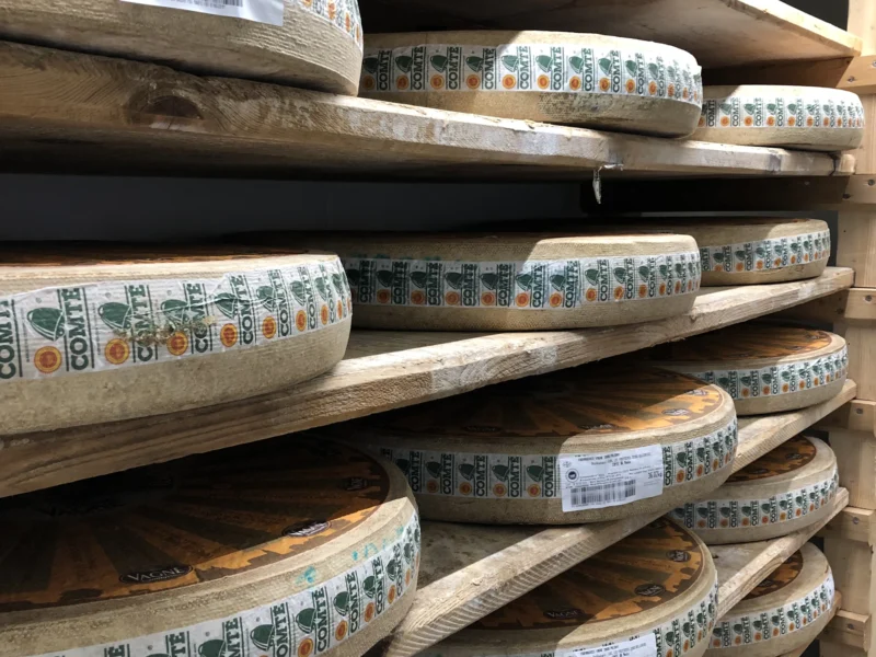 Meules de comté alignées sur des planches d’épicéa dans une cave d’affinage